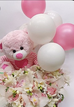 5 pink and white balloons attached to a basket with white lilies and pink and white roses and pink teddy bear 6 inches