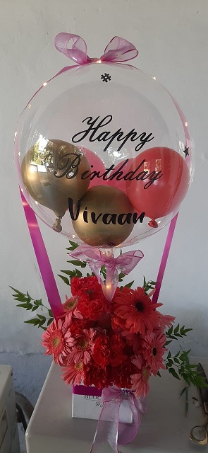 Bouquet of clear printed happy birthday transparent balloon with NAME printed 12 pink gerbera and rose in the balloon wrapped in pink ribbons and led lights