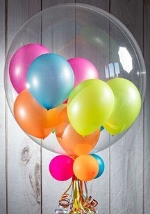 Multi color small balloons inside a clear bobo balloon with 4 balloons and foliage trailing on stick