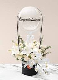 6 White Lilies and 10 white roses tied with black ribbon to a balloon with print congratulations