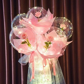 Five pink roses stuffed in 5 transparent balloons decorated with pink and white wrapping