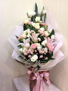 3 Light pink Lilies with 20 peach roses and 10 white roses in a bouquet wrapped in net and tied with pink ribbons